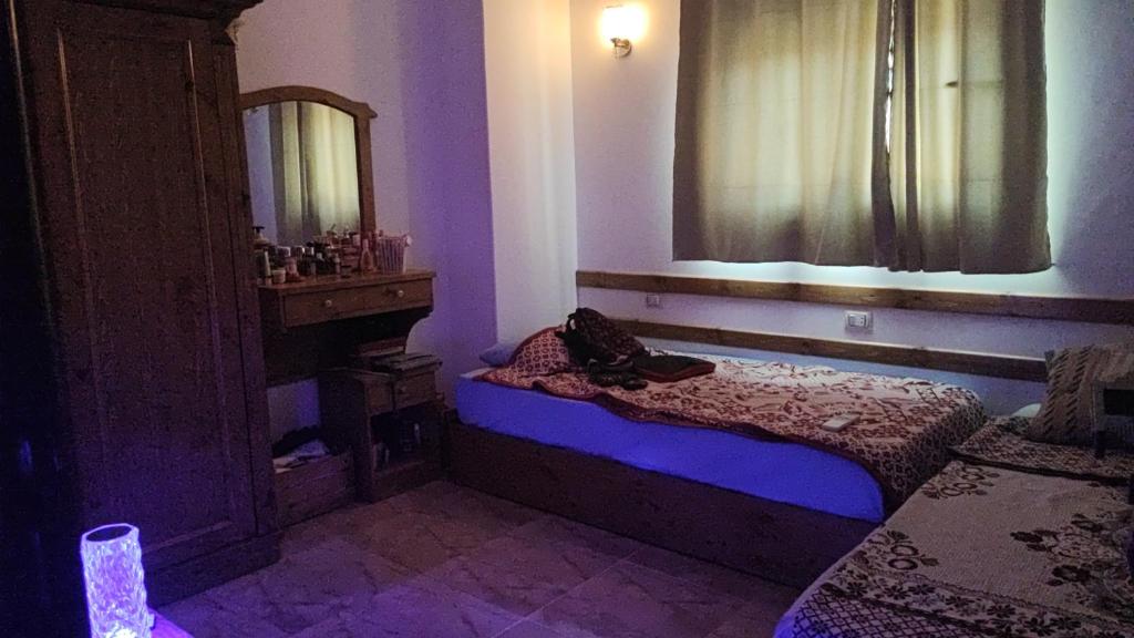 Habitación oscura con cama y espejo. en Sara's home, en Dahab