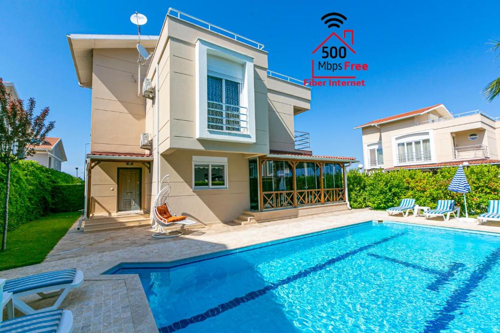 a villa with a swimming pool in front of a house at Paradise Town Villa Beltania 500 MBPS free wifi in Belek