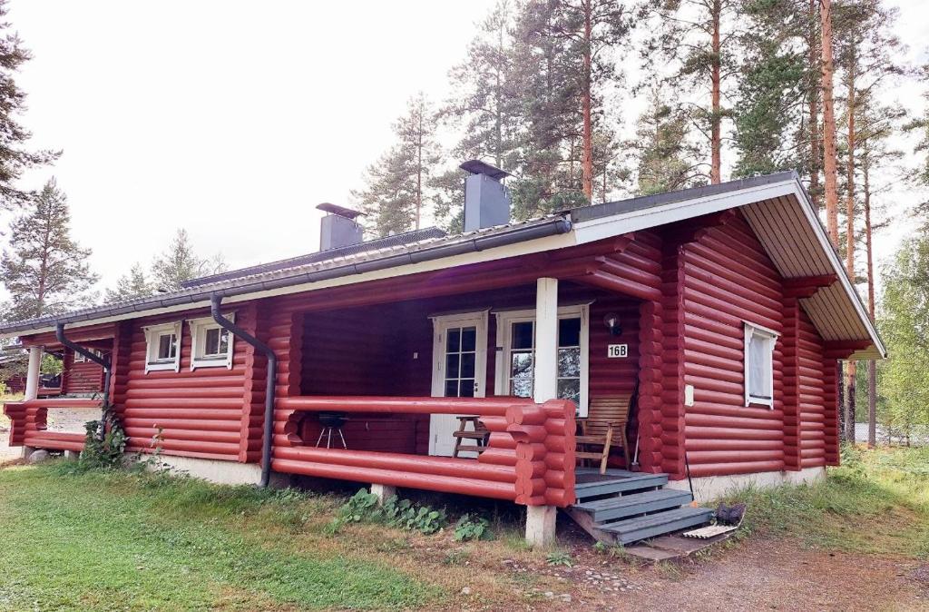 eine rote Hütte im Wald mit einer Veranda in der Unterkunft Pankkotupa 16-B in Punkaharju