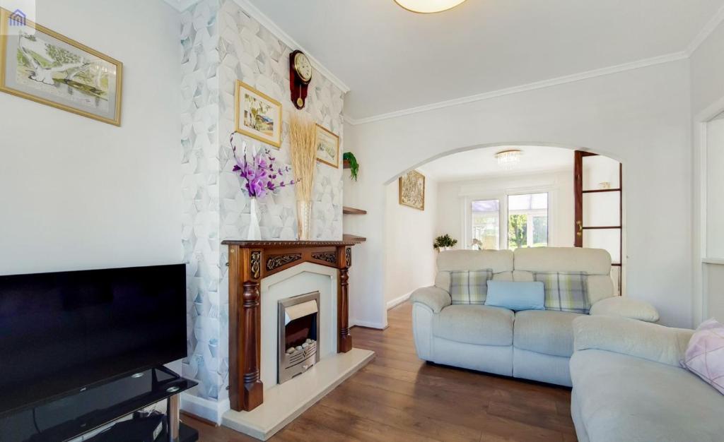 a living room with white furniture and a fireplace at EEJs Charming London 6 bedroom home - with large garden in London