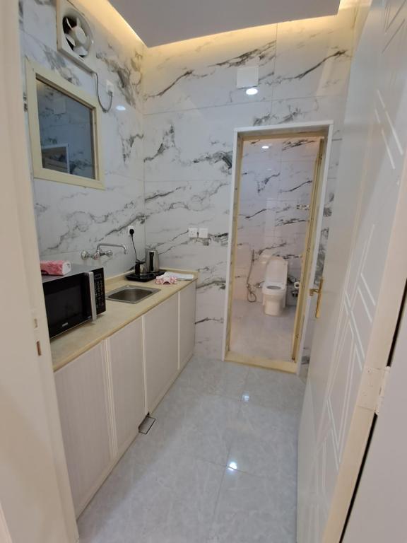 a bathroom with a white marble wall at نسيم العوالي in Ash Shishah