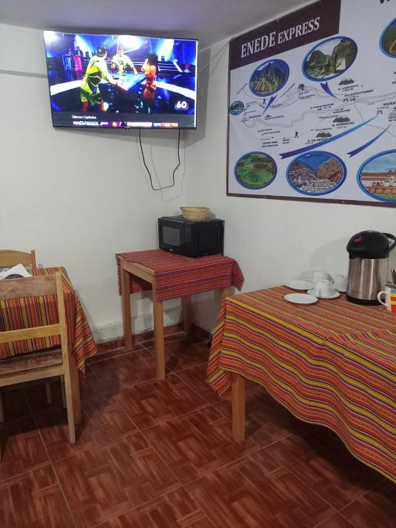 a room with a tv on the wall and a table at ENEDE HOSTEL in Cusco