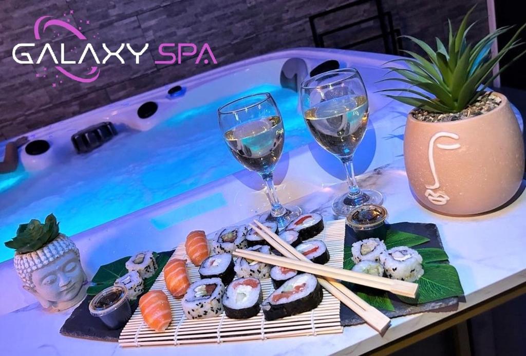 - une table avec des sushis et 2 verres de vin dans l'établissement GALAXY SPA - Suite Jupiter Jacuzzi Privatif, à Champigneulles