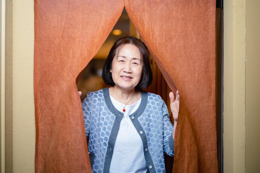 Eine Frau, die hinter einem Vorhang hinausschaut in der Unterkunft ホステル祇園SORA in Kyoto