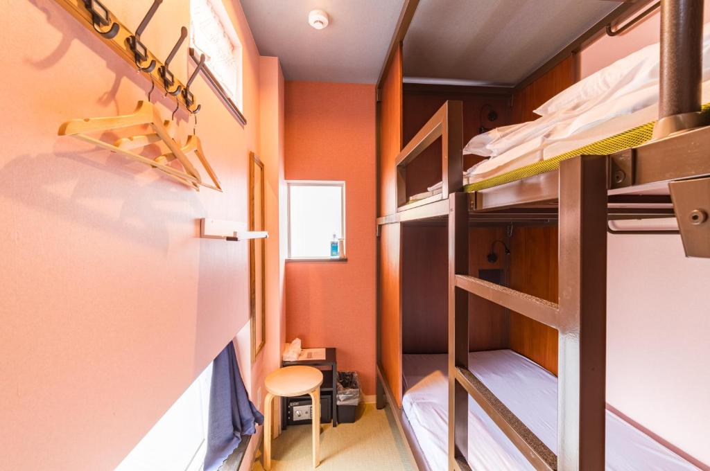 Mały pokój z łóżkiem piętrowym i krzesłem w obiekcie ホステル祇園SORA w mieście Kioto