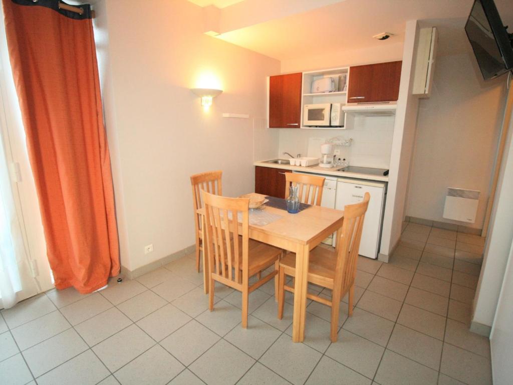 une petite cuisine avec une table et des chaises en bois dans l'établissement Appartement T2 avec piscine, proche plage et centre, La Tranche sur Mer - FR-1-22-316, à La Tranche-sur-Mer