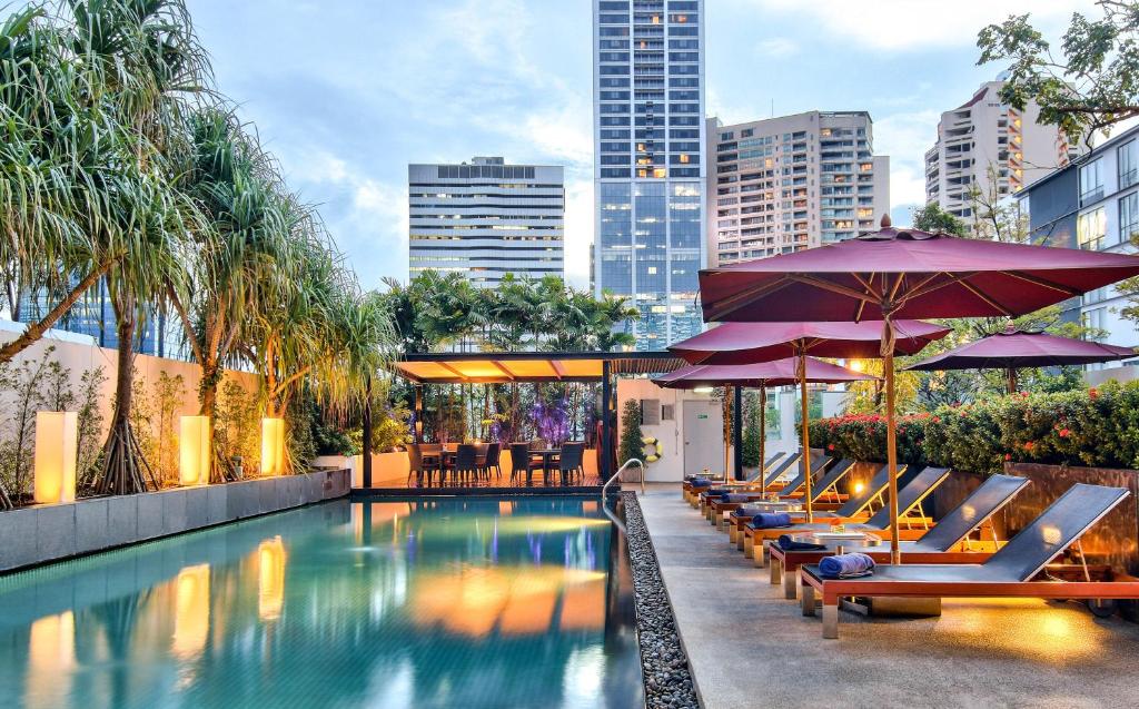 een zwembad met ligstoelen en parasols bij Park Plaza Bangkok Soi 18 in Bangkok