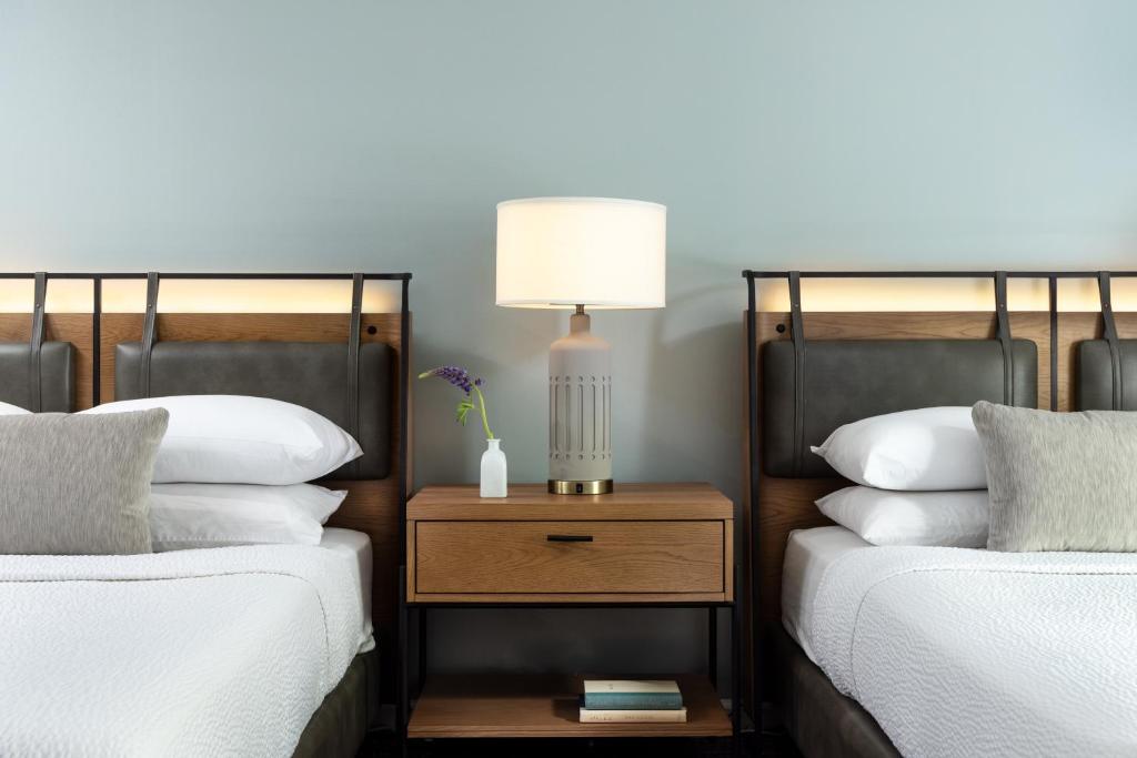 twee bedden met witte kussens en een lamp op een nachtkastje bij Meadowbrook Inn in Blowing Rock