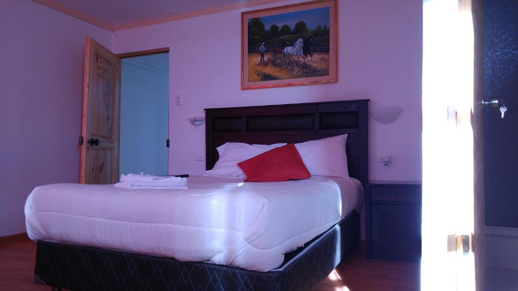 a bedroom with a large white bed with red pillows at Hostal America in Calama