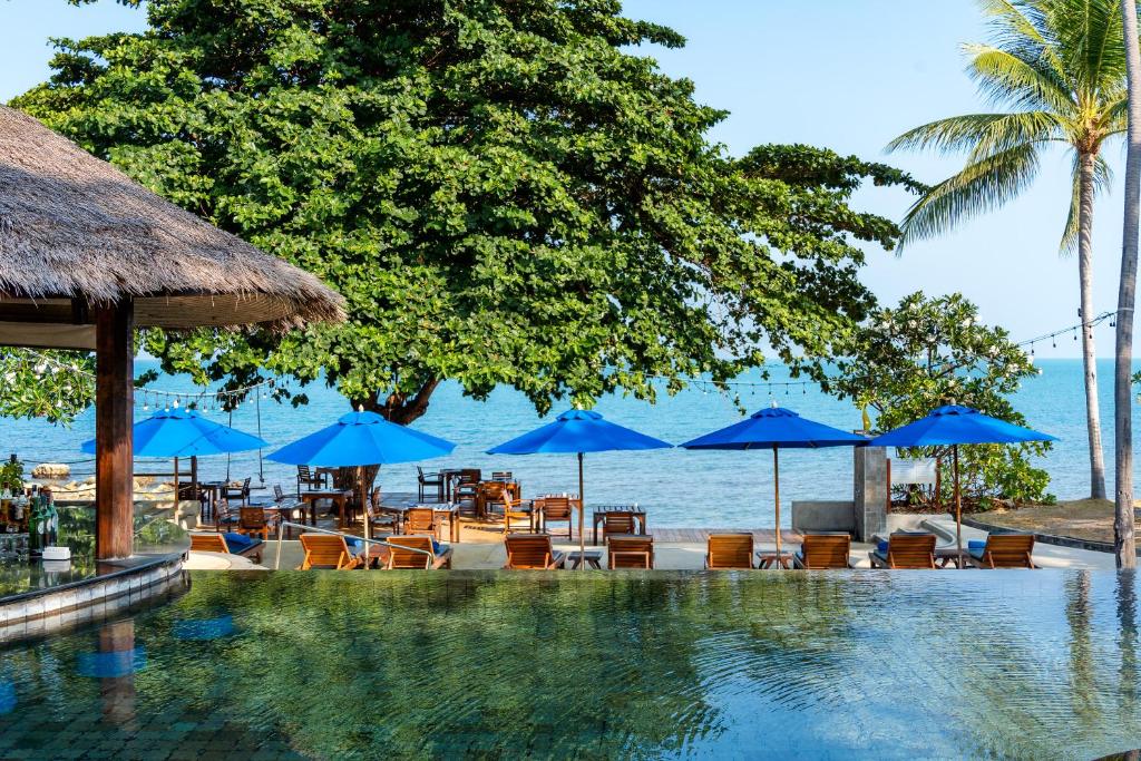 una piscina con sillas y sombrillas azules en SAii Koh Samui Choengmon en Choeng Mon Beach