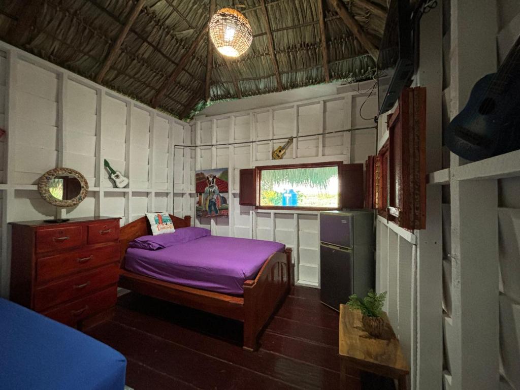 Un pequeño dormitorio con una cama morada y una ventana en Sea la vie casita en Las Peñitas