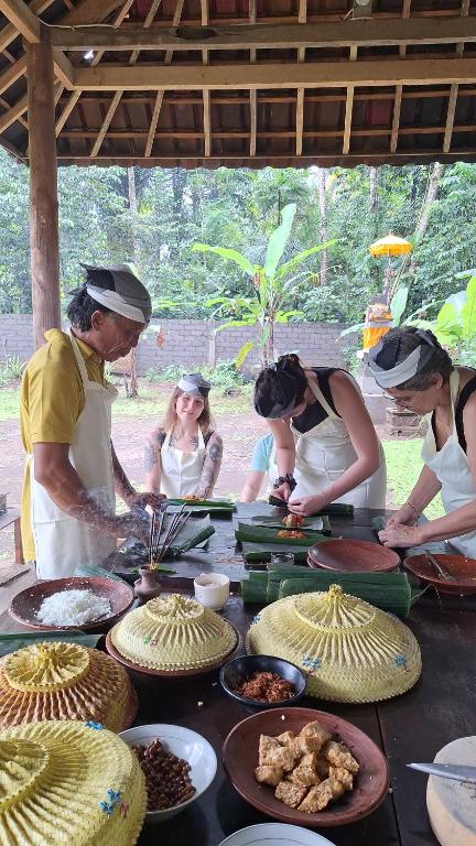 un grupo de personas de pie alrededor de una mesa con comida en Pondok Masa Depan, en Sidemen