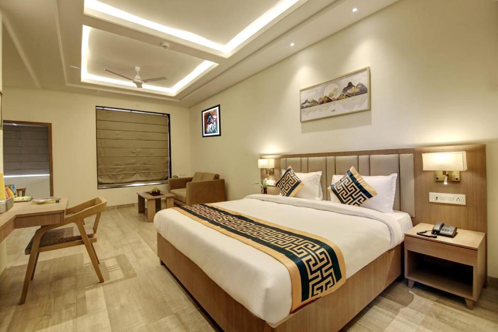 a hotel room with a large bed and a desk at Hotel King Plaza in New Delhi