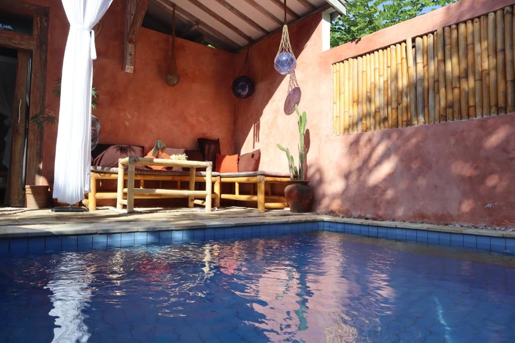 a house with a swimming pool with a table and a couch at Villa Sea La Vie Private pool in Gili Meno