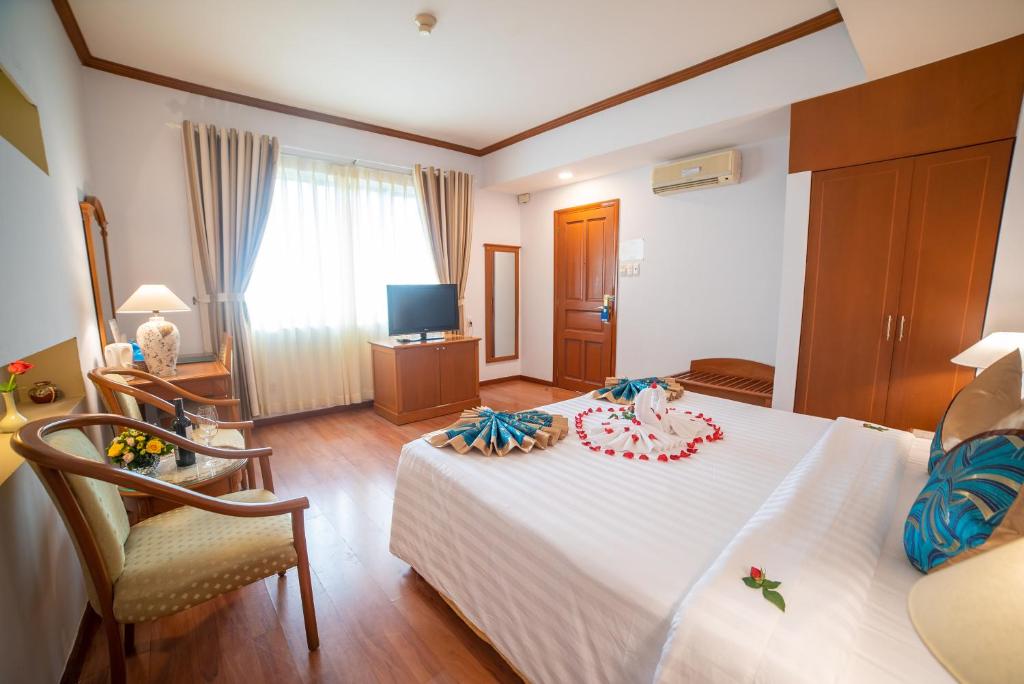 a bedroom with a white bed and a television at Oscar Saigon Hotel in Ho Chi Minh City