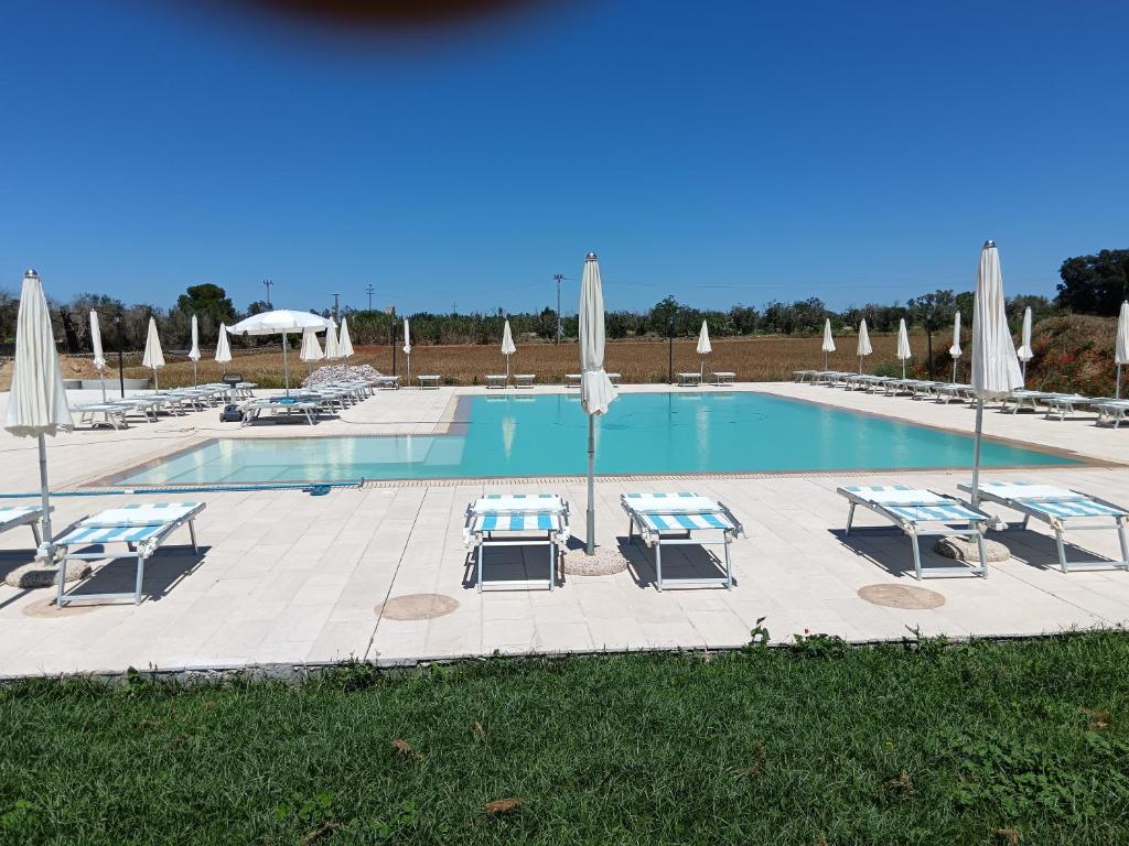 una piscina con mesas, sombrillas y sillas en Masseria Cricelli, en Lizzanello