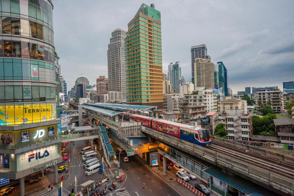 un tren en una pista en una ciudad con edificios en The Westin Grande Sukhumvit, Bangkok, en Bangkok