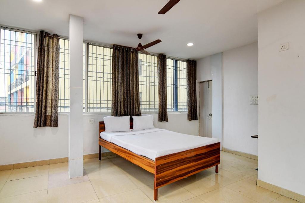 1 dormitorio con 1 cama con sábanas blancas y ventanas en OYO Hotel Lake View en Ranchi