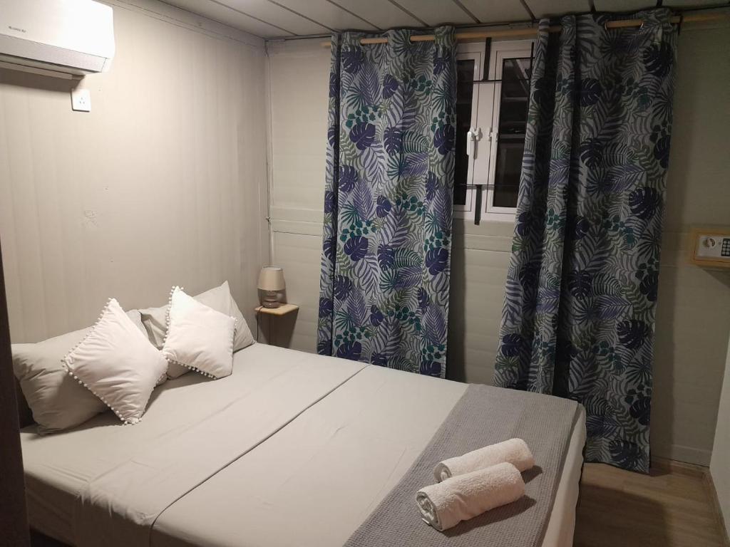 - une chambre avec un grand lit blanc et des rideaux bleus dans l'établissement Tilakaz Kreol, à Pointe d'Esny