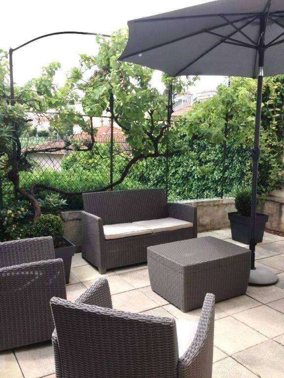 une terrasse avec des chaises en osier, une table et un parasol dans l'établissement Cannes Little House, à Cannes