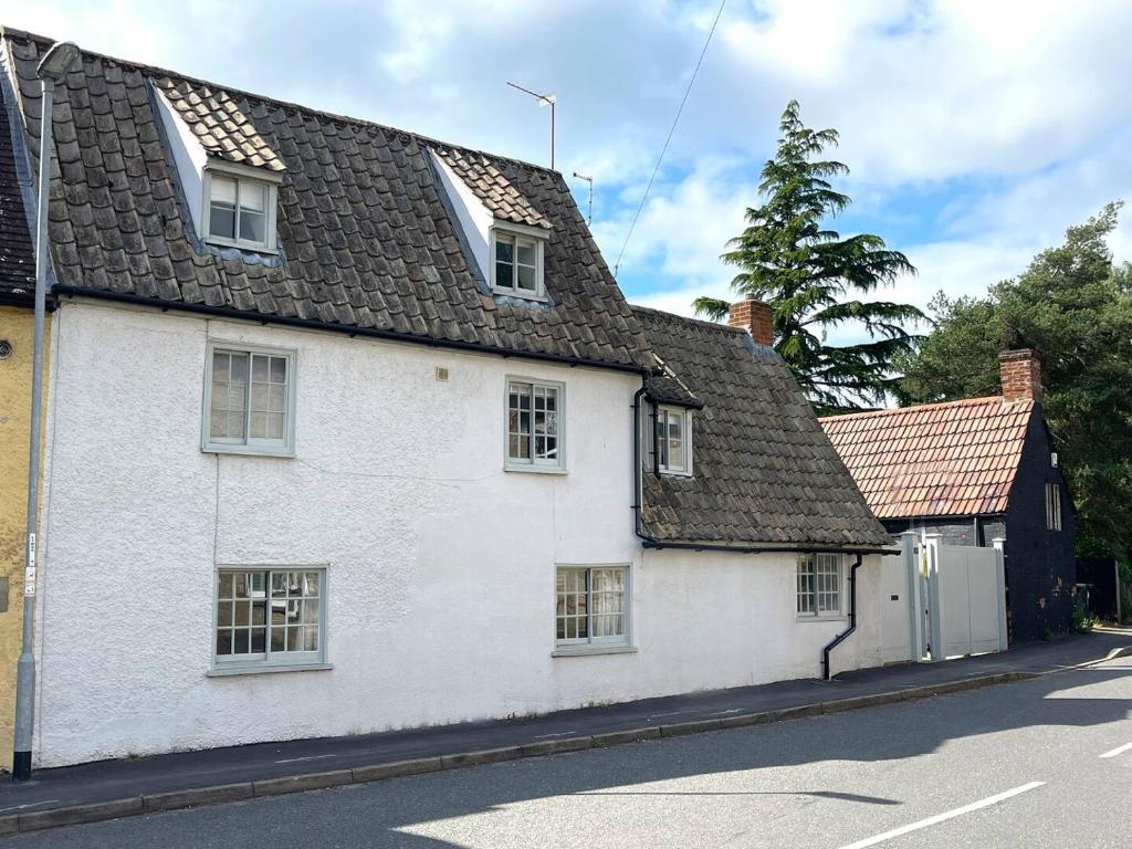 a white house with windows on a street at Elegant Oak Beamed House In Pretty Village - Cambridge Homehost in Buckden