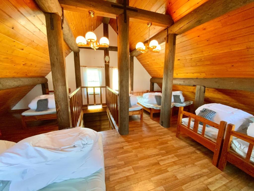 1 Schlafzimmer mit 3 Betten in einem Zimmer mit Holzdecken in der Unterkunft Mashuko Youth Hostel - Vacation STAY 01026v in Teshikaga