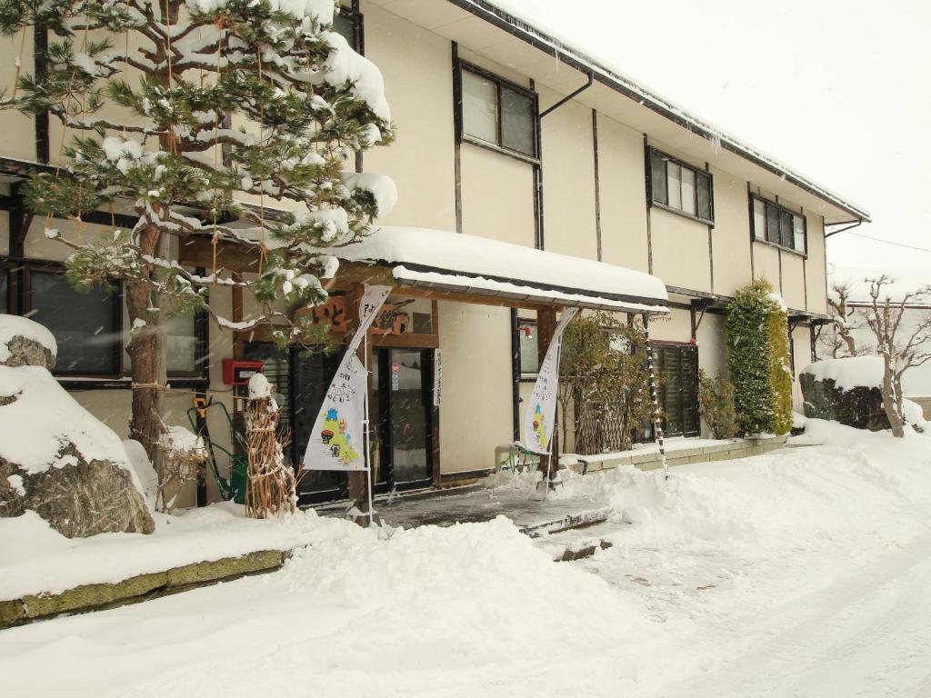 a building with a pile of snow in front of it at Itoya Ryokan in Nanyo