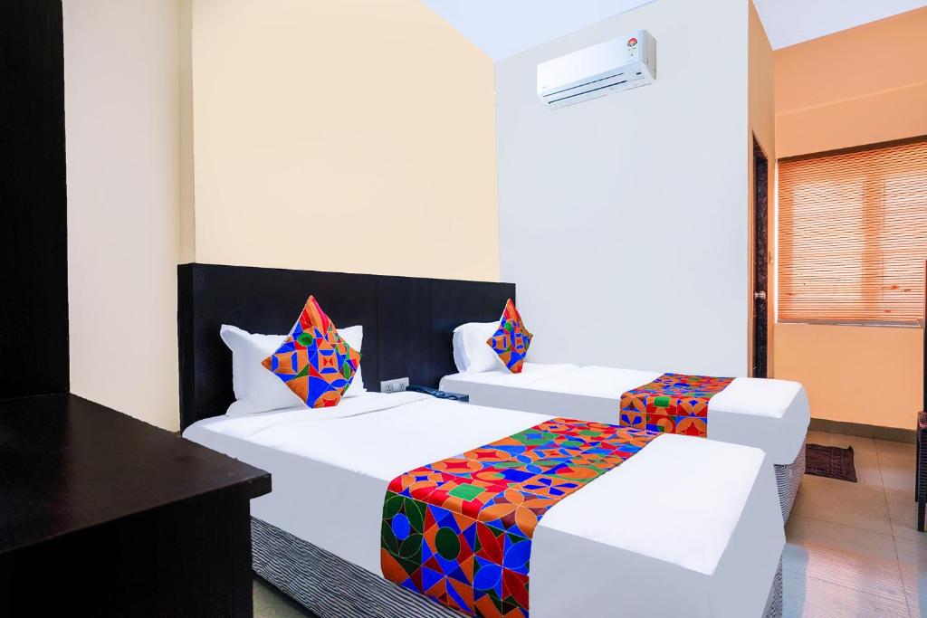 FabHotel Serenity في Gachibowli: غرفة في الفندق مع سريرين مع وسائد ملونة