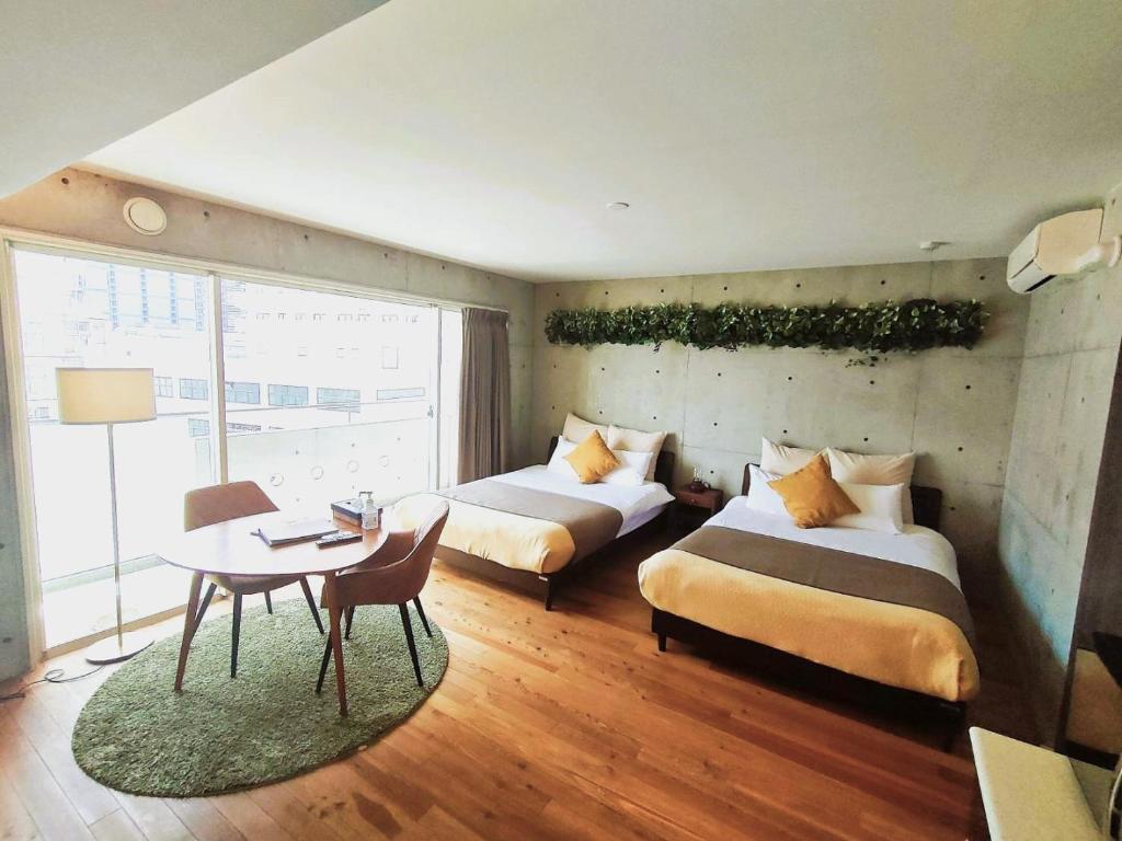 pokój hotelowy z dwoma łóżkami i stołem oraz tableablish w obiekcie TAKETO STAY Osakajo w Osace