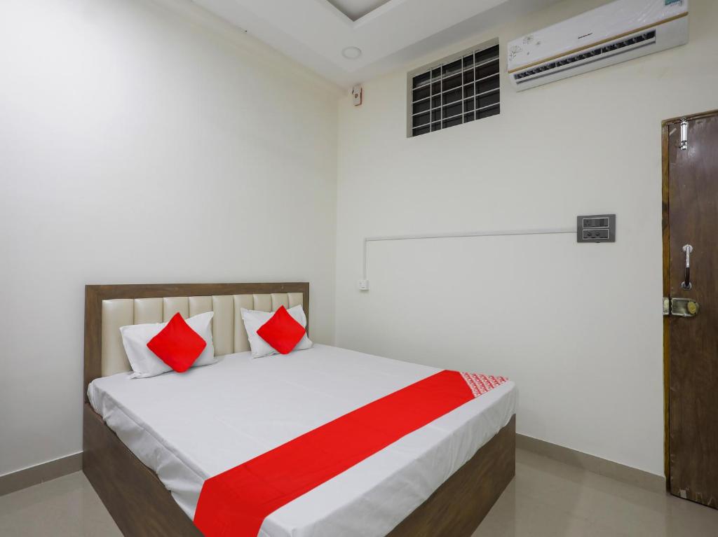 Schlafzimmer mit einem Bett mit roten und weißen Kissen in der Unterkunft OYO Flagship Hotel Rahul Service Appartment 2 in Nagpur