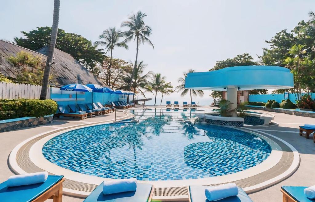 a pool at a resort with blue chairs and the ocean at MATCHA SAMUI RESORT formerly Chaba Samui Resort in Chaweng