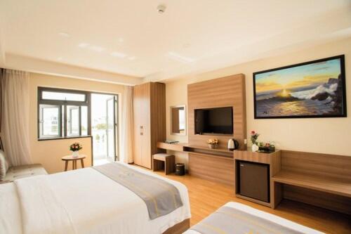 ニャチャンにあるOrbit Hotelのベッド1台、薄型テレビが備わるホテルルームです。