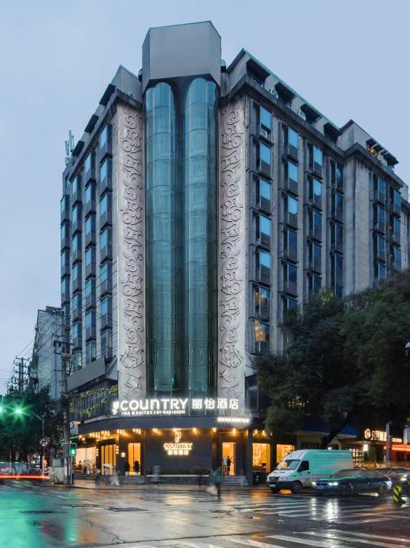 a building on a street with cars in front of it at Country Inn & Suite by Radisson, Nanchang Tengwangge Wanshou Palace Subway Station in Nanchang