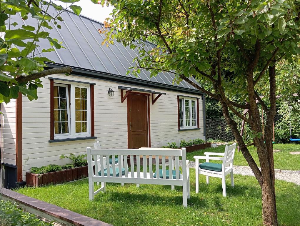 deux bancs blancs assis devant une maison dans l'établissement Dwie Chatki domek, à Sandomierz