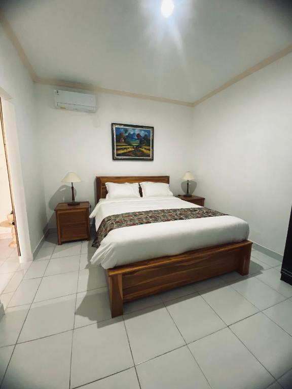 a bedroom with a large bed and two night stands at Pondok Dauh Ancak in Tabanan