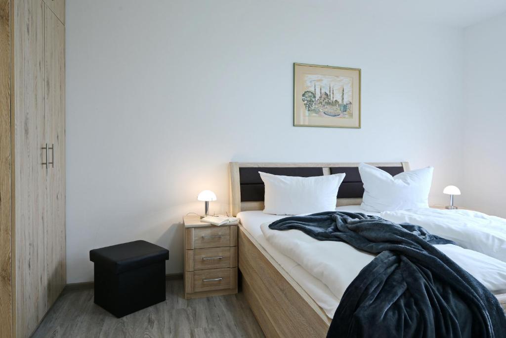 a bedroom with a bed with white sheets and a black blanket at Fewo 61 Hogwarts in Sagard