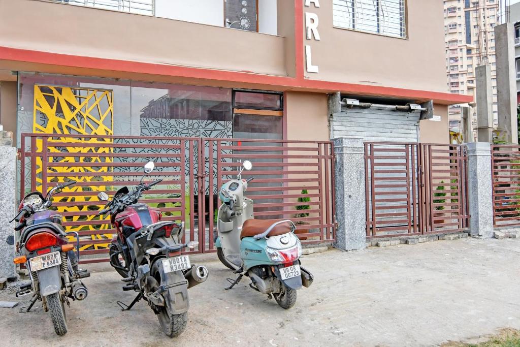 drie motorfietsen geparkeerd voor een gebouw bij The Blue Pearl Hotel in Calcutta