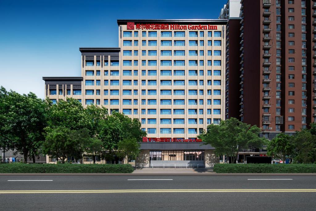 ein hohes Gebäude mit einem roten Schild darauf in der Unterkunft Hilton Garden Inn Beijing West Railway Station in Peking