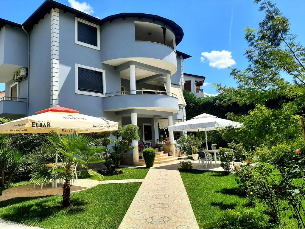 a large building with an umbrella and a garden at Hotel Vila Arbri in Berat