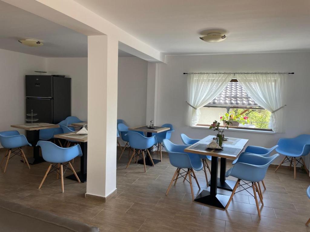 a dining room with blue chairs and tables and a window at Casa Hoinarilor Wanderers House in Bran