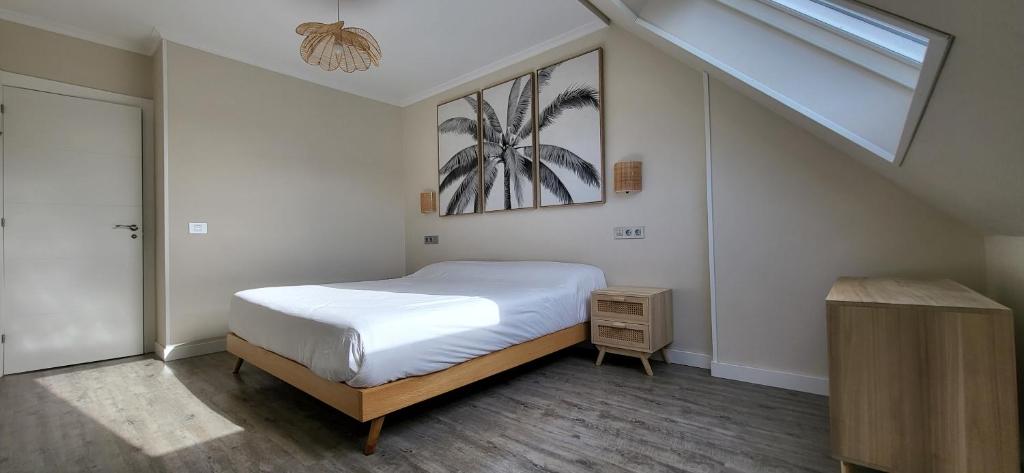 a bedroom with a white bed and a skylight at Las Gaviotas in Viveiro