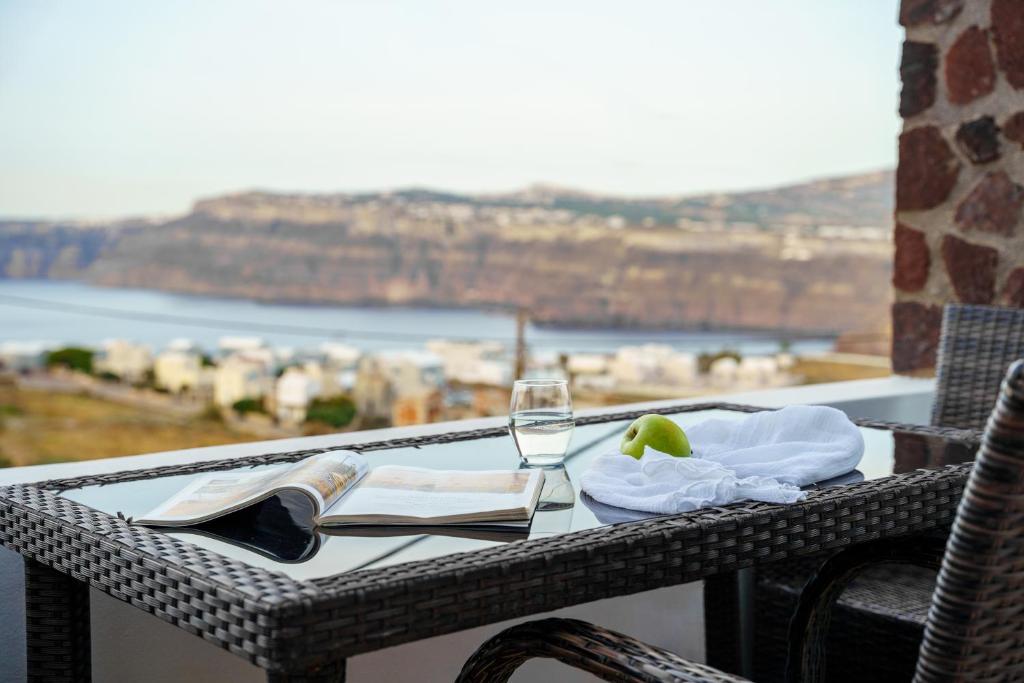 アクロティリにあるAnya Suites Santoriniのバルコニーにテーブルとワイン1杯