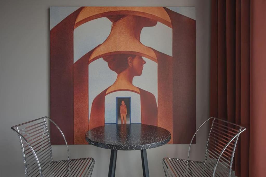 a table in a room with a painting of a woman at Resume apartments, Dreamer Corner No1 by Urban Rent in Kaunas