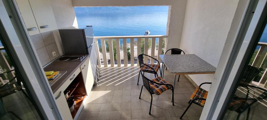 a kitchen with a table and a balcony with the ocean at Villa Ana in Slatine