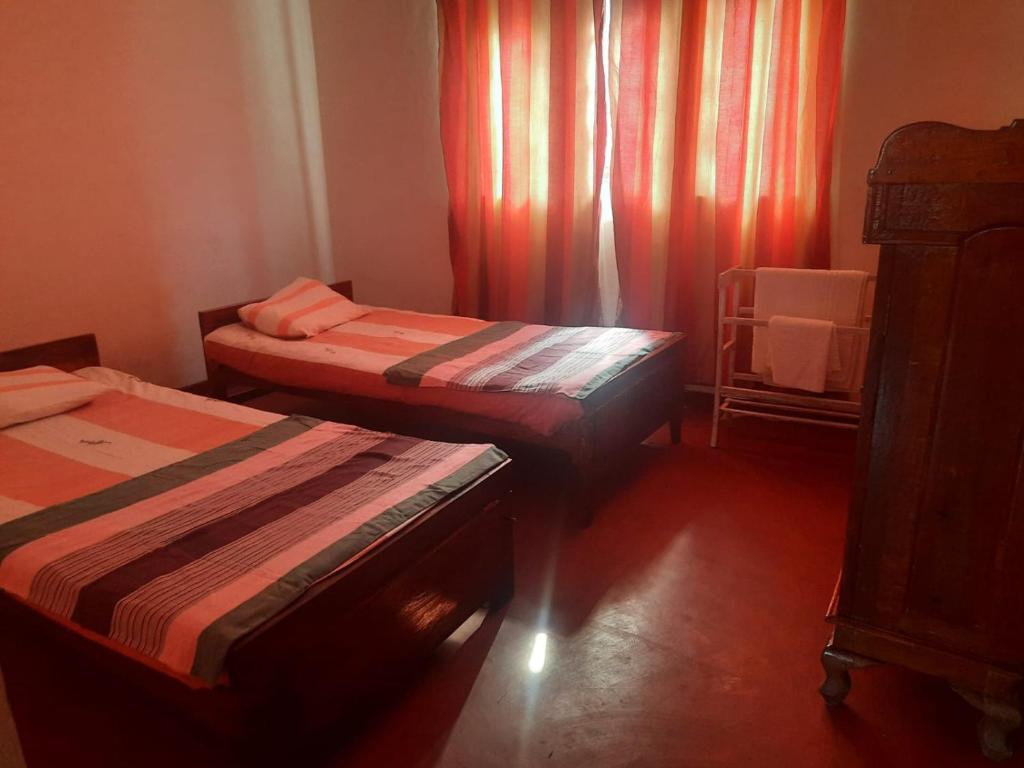 康提的住宿－Kandyan Paradise，橙色窗帘间内的两张床