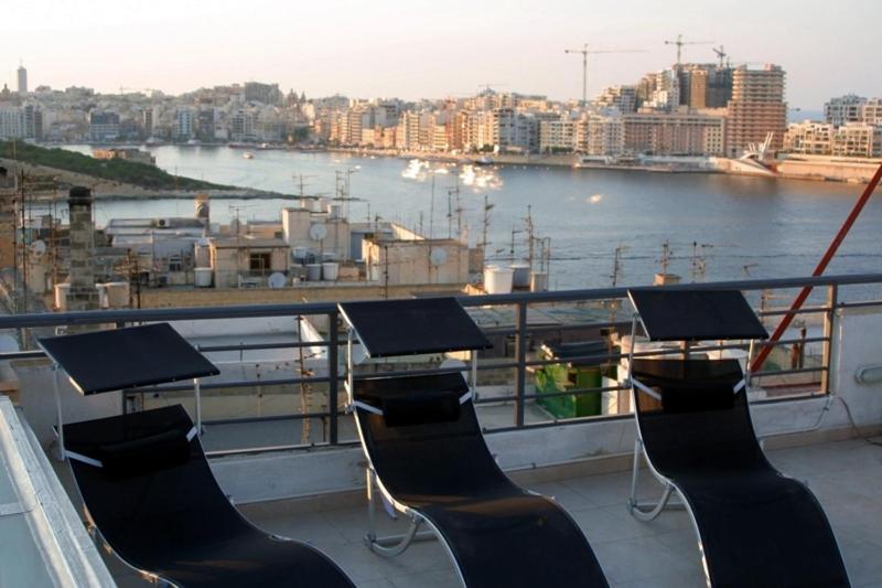 balkon z krzesłami i widokiem na wodę w obiekcie Old Mint Penthouse w mieście Valletta
