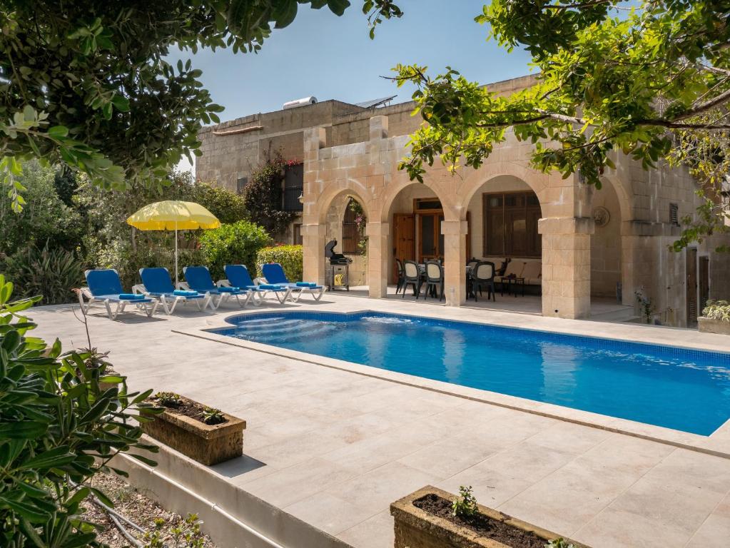 einen Außenpool mit Stühlen und einem Sonnenschirm in der Unterkunft Dar Is-Sultan Farmhouse in Il-Wilġa