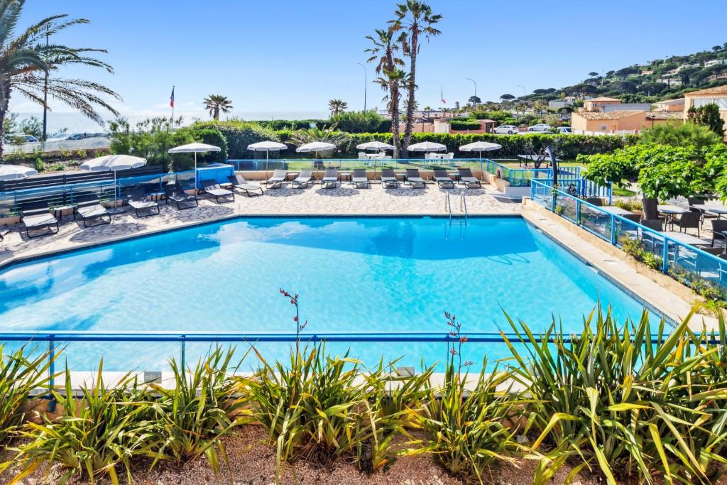 a pool with chairs and umbrellas at a resort at Hôtel La Nartelle in Sainte-Maxime