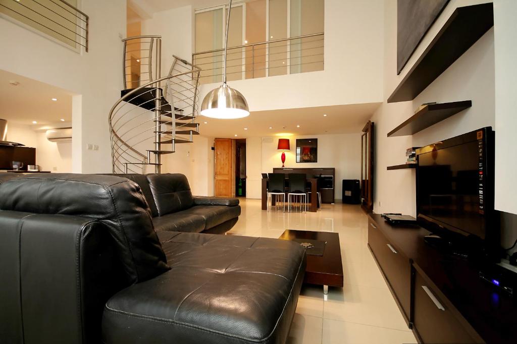 uma sala de estar com um sofá de couro e uma televisão em Old Mint No1 em Valletta