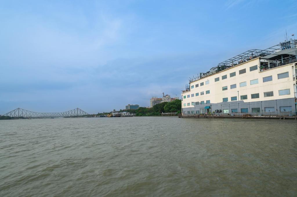 Blick auf einen Fluss mit einem Gebäude und einer Brücke in der Unterkunft Polo Floatel Kolkata in Kalkutta